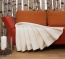 Plüschdecke in hellem Naturton ausgebreitet auf einem Sofa