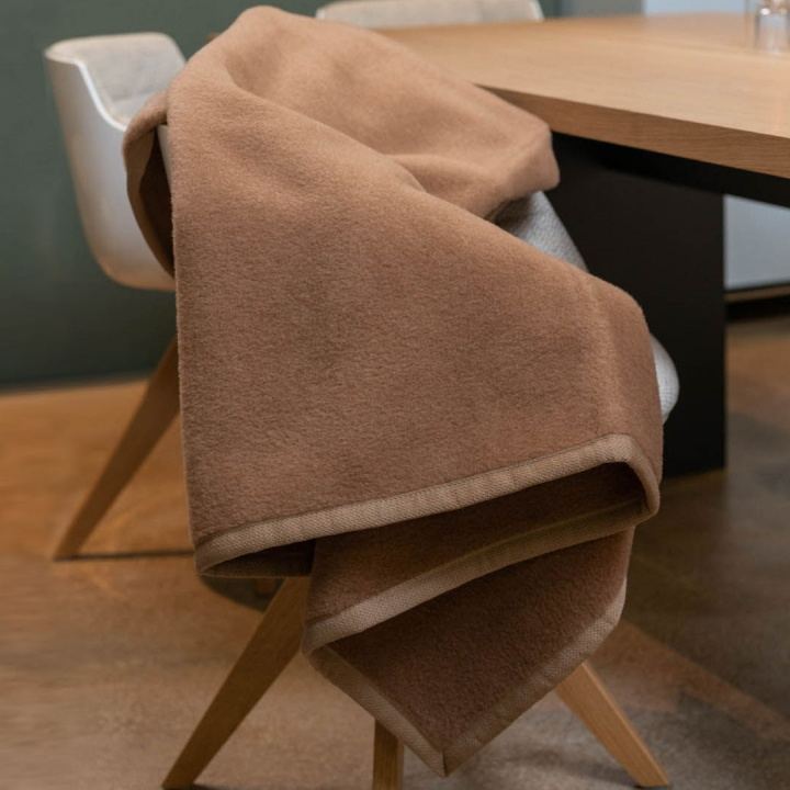 Kuscheldecke in hellem braun ausgebreitet über einem Stuhl Kuscheldecke in hellem braun ausgebreitet über einem Stuhl