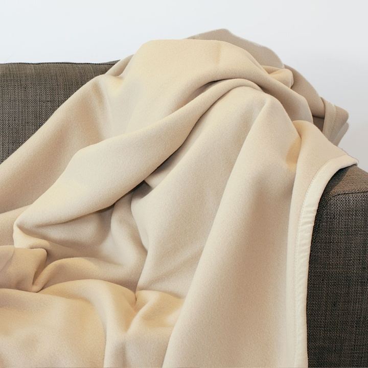 Heimdecke aus Cashmere und Merino-Lammwolle ausgebreitet auf einer Couch Heimdecke aus Cashmere und Merino-Lammwolle ausgebreitet auf einer Couch