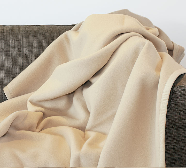 Heimdecke aus Cashmere und Merino-Lammwolle ausgebreitet auf einer Couch Heimdecke aus Cashmere und Merino-Lammwolle ausgebreitet auf einer Couch